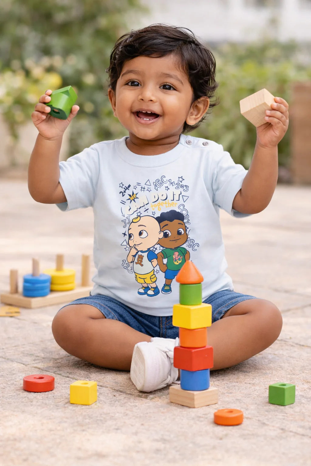 Playful Toddler Sitting Outdoors with Building Blocks in Cartoon T-Shirt